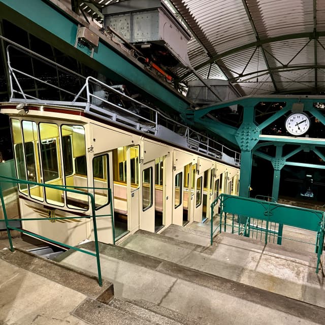 Historische Dresdner Schwebebahn in der beleuchteten Bergstation bei Nacht mit gelb-weißen Waggons und Metallkonstruktion